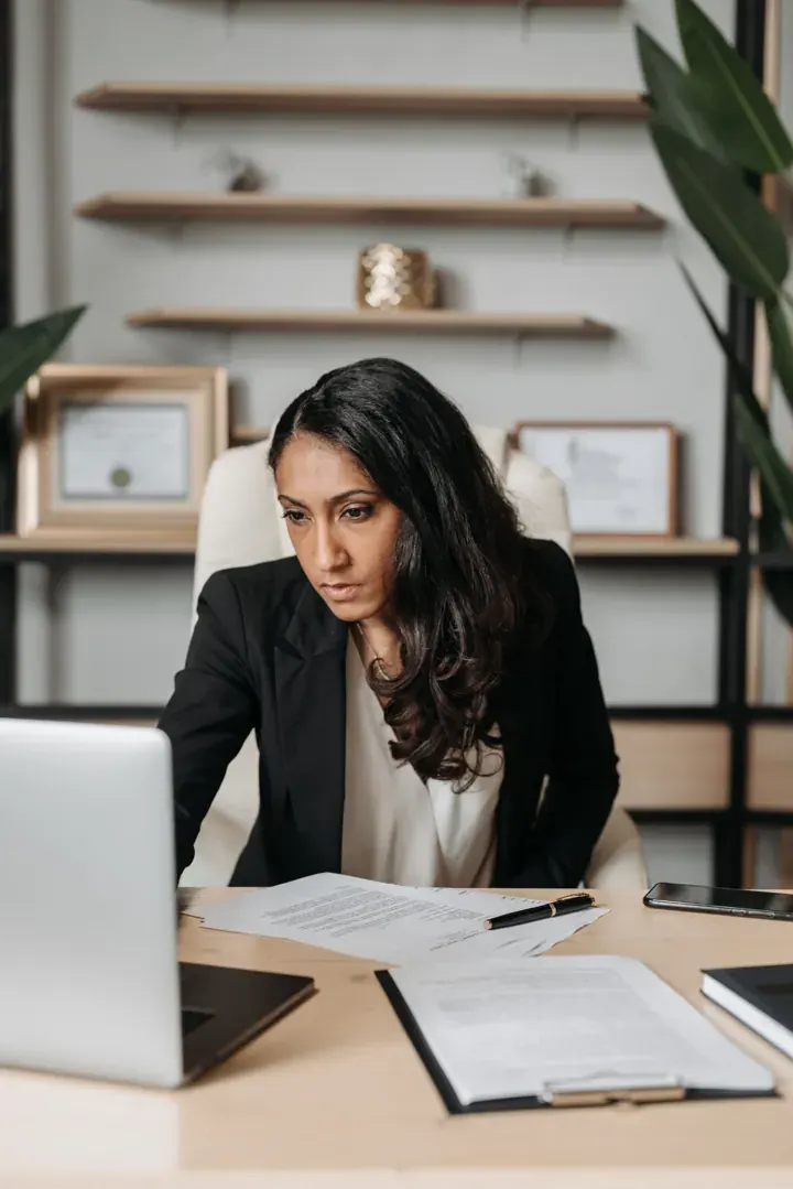 An attorney at her desk, reading documents beside a laptop